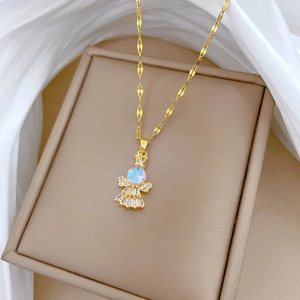 Close-up of golden titanium necklace with angel pendant on beige jewelry box and silk