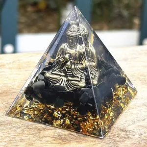 Orgonite pyramid with golden Buddha statue and obsidian crystals on a wooden base