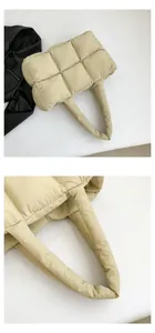 Close-up of beige quilted down puffer tote bag showing padded handle and stitching detail