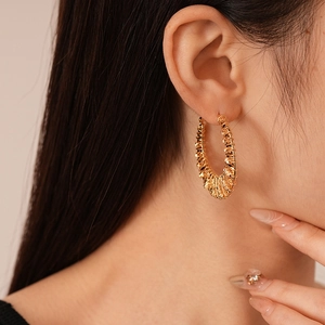 Gros plan d'une boucle d'oreille créole dorée avec texture perlée sur un mannequin