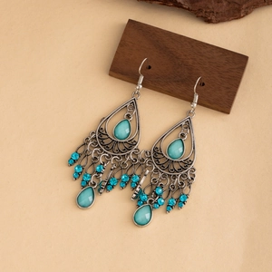 Boucles d'oreilles bohèmes argentées avec pierres bleues et glands sur support bois