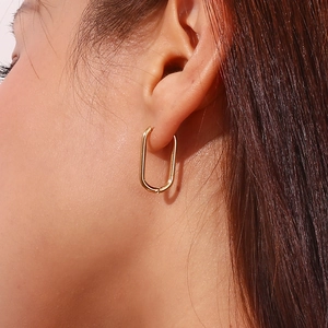 Close-up of model wearing 18K gold plated U-shaped oval hoop earrings in stainless steel