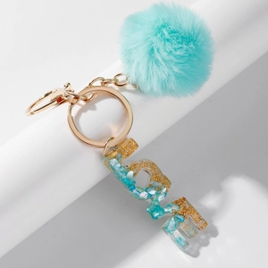 Macro detail of LOVE letter resin keychain with mint green pompom and gold flakes