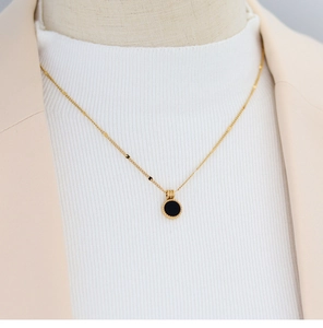 Minimalist black round shell pendant necklace styled with beige blazer and white knitwear