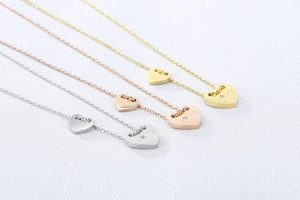 Detail von Herzanhängern in Silber, Roségold und Gold mit LOVE-Gravur und kleinem Kristall