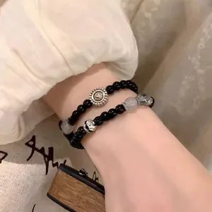Close-up of black obsidian beaded bracelet with vintage silver charms on a model wrist