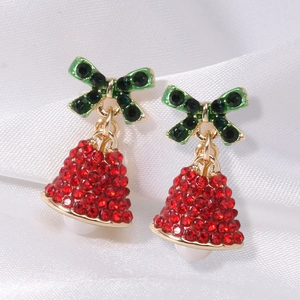 Detailed macro view of rhinestone-encrusted red Christmas bell earrings on silk