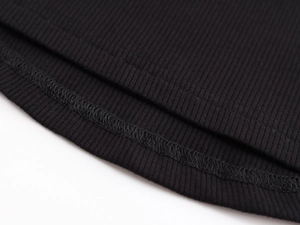 Detail of black ribbed knit fabric showing elastic texture and double-stitched hem finish