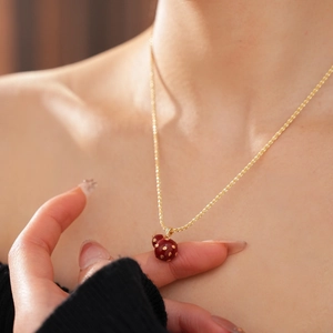 Close-up of a model wearing an 18k gold-plated necklace with a red gourd-shaped pendant