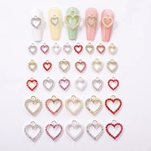 Close-up of heart-shaped alloy charms with rhinestones for DIY festive nail art decor
