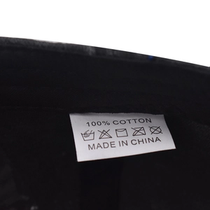 Détail de l'étiquette d'entretien d'une casquette 100% coton montrant les icônes de lavage
