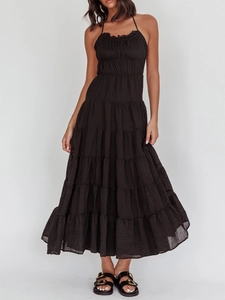 Detail of a black backless halter tiered maxi dress showing layered flowy fabric
