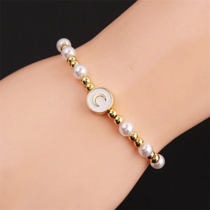 Detail of beaded moon bracelet with pearls and golden beads on woman's wrist