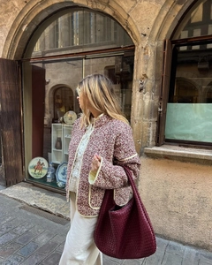 Detail of vintage quilted floral cotton jacket with Intrecciato woven tote bag outdoors
