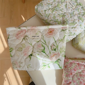 Detail of floral quilted cotton makeup bags with zippers in pink and green patterns