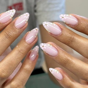 Macro detail of almond press-on nails with pink jelly base and floral patterns