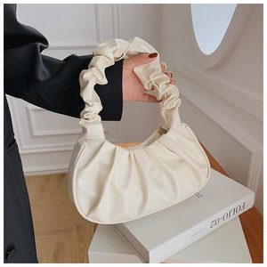 Detail of white pleated cloud handbag held by model in black blazer for elegant style