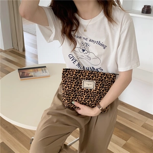 Detail of leopard print canvas makeup bag featuring a white woven label and zipper closure