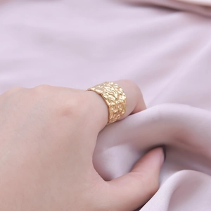 Close-up of golden wide band ring featuring a hand-hammered irregular texture finish