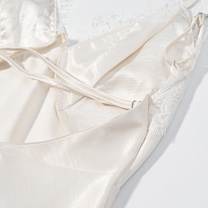 Close-up of white satin dress back showing intricate lace trim and silky texture details