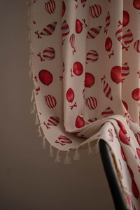 Close-up of beige cotton linen Christmas curtain featuring festive tassels and red patterns