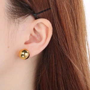 Close-up of a model wearing a minimalist 18K gold plated spherical stud earring