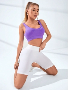 Dettaglio del top sportivo viola a coste e degli shorts da yoga bianchi a vita alta