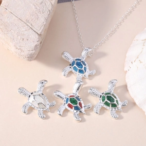 Polished sea turtle opal necklaces in four colors with shells on a sand background