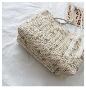 Detail view of widened straw tote bag base with floral embroidery and lace trim