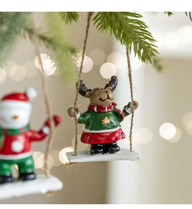 Macro shot of reindeer in a red dress on a swing, festive resin Christmas tree decoration