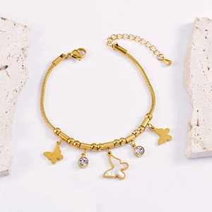 Golden butterfly bracelet with zircon accents and white shell inlay on stone props