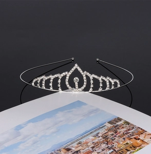 Close-up of silver bridal crown with sparkling rhinestones on a black reflective surface