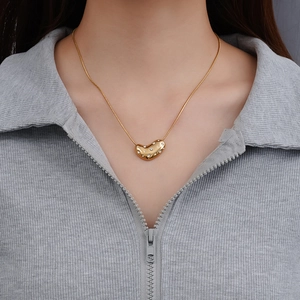 Gold titanium chain necklace with sparkling crystal bean pendant on model's neck