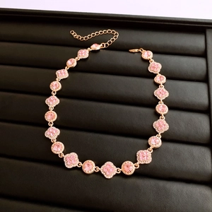 Détail macro du collier trèfle en or rose avec pierre rose sur plateau noir