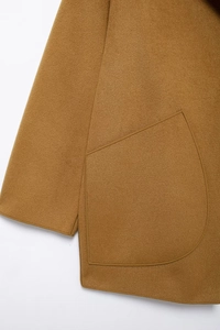 Detail shot of the caramel wool coat showing stitching and pocket craft on the sleeve