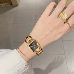 Detail of elegant gold square watch with black dial and hollow chain strap on wrist