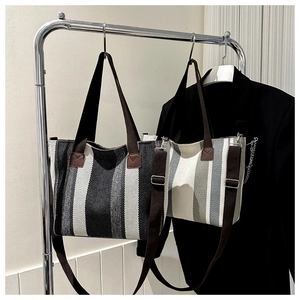 Detail of striped woven tote bags in black and beige on display racks with long straps