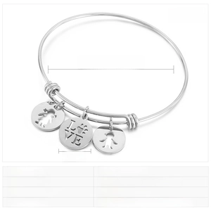 Detail of adjustable gold stainless steel bracelet with engraved boy, girl, and love pendants