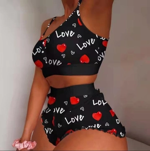 Detail of one-shoulder pajama set with red hearts and Love lettering on black fabric