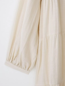 Detail of beige cotton linen dress showing elastic cuffs and pleated fabric texture