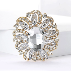 Detailed view of a gold floral brooch with oval glass crystal and rhinestones