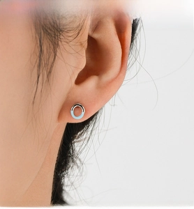 Macro shot of a 925 silver geometric earring with light blue enamel on a model ear