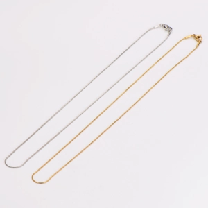 Detail of 1mm stainless steel snake bone chain necklaces in gold and silver finish