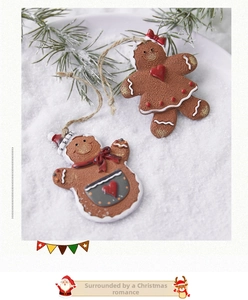 Detail of gingerbread man and woman ornaments with icing details on pine branches