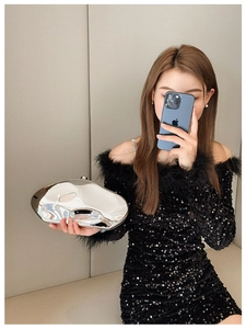 Close-up of irregular silver metallic clutch with mirror finish held by model