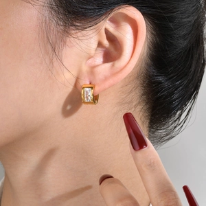 Detail of gold U-shaped huggie earrings with rectangle cut cubic zirconia on ear