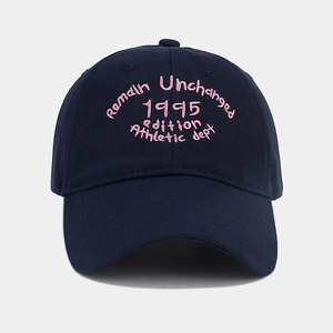 Detail of pink vintage embroidery on navy blue cotton baseball cap with text texture