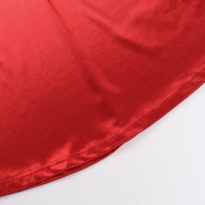 Macro view of red satin fabric texture and precise stitching on the hem of the dress