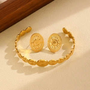 Macro detail of golden bohemian sunburst relief on stainless steel bangle and earrings