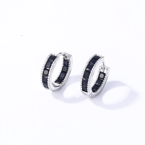 Macro detail of silver hoop earrings featuring channel-set square black gemstones